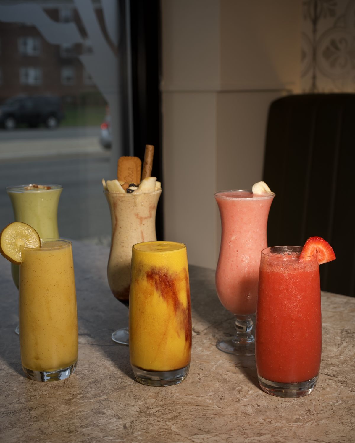 Five fresh juices lined up along the marble counter